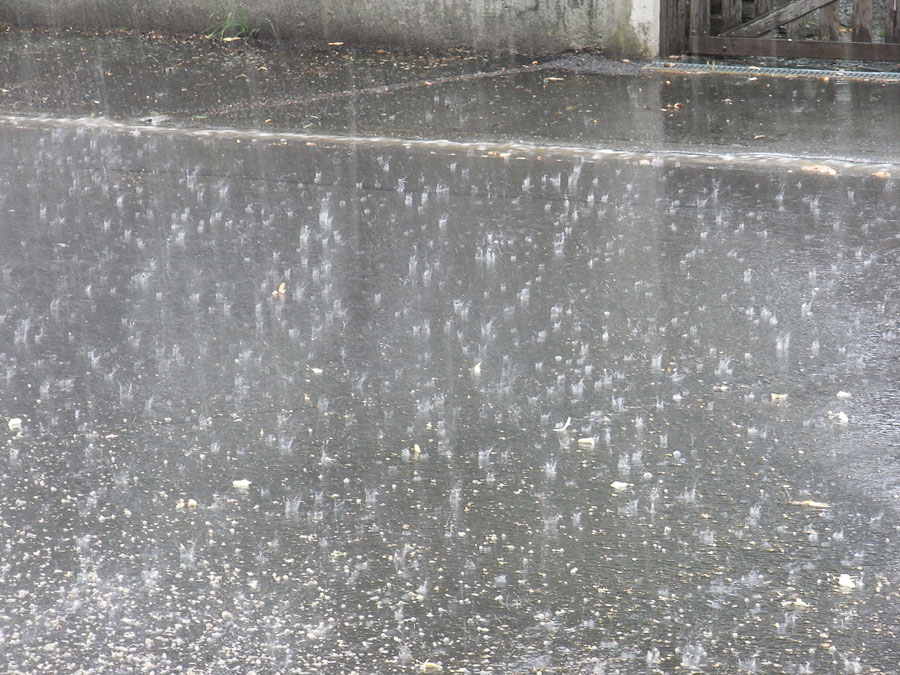 Starkregen, der auf eine geteerte Straße fällt, die im Begriff steht, überflutet zu werden.